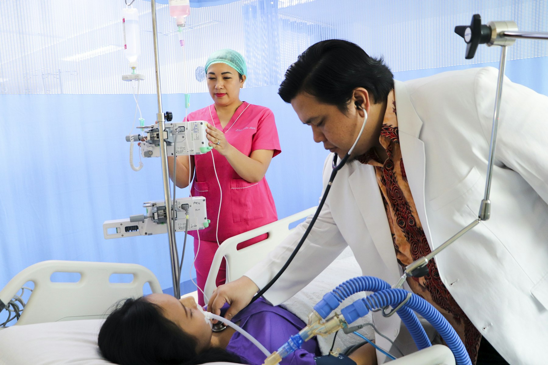 Doctor examining a patient in the ICU while heart pump support is monitored
