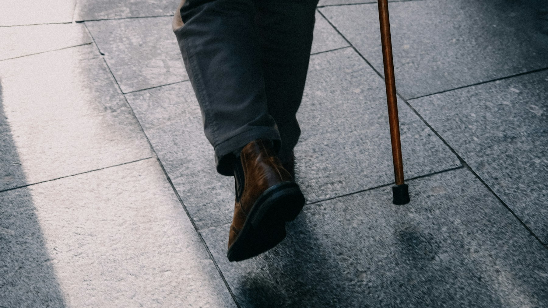 Close-up of a person walking with a cane, as leg cramping during activity can be a sign of a narrowed artery